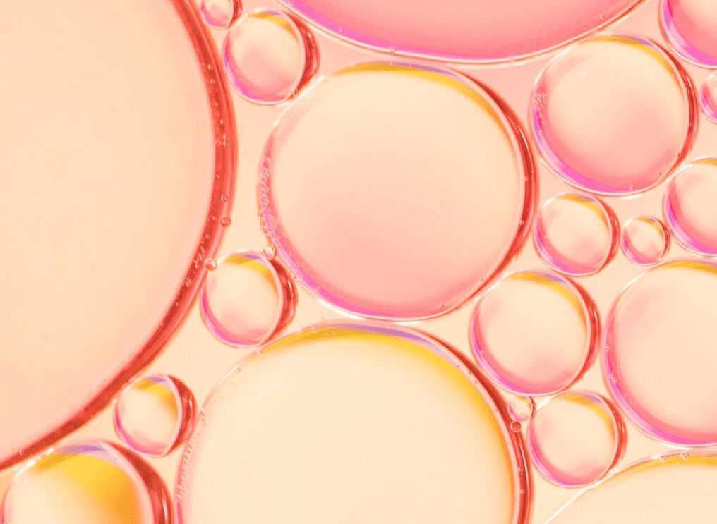 A background image of pink and yellow bubbles, symbolizing skin health. The text highlights clinically proven anti-aging results on all skin types, even the most sensitive, without side effects. A 